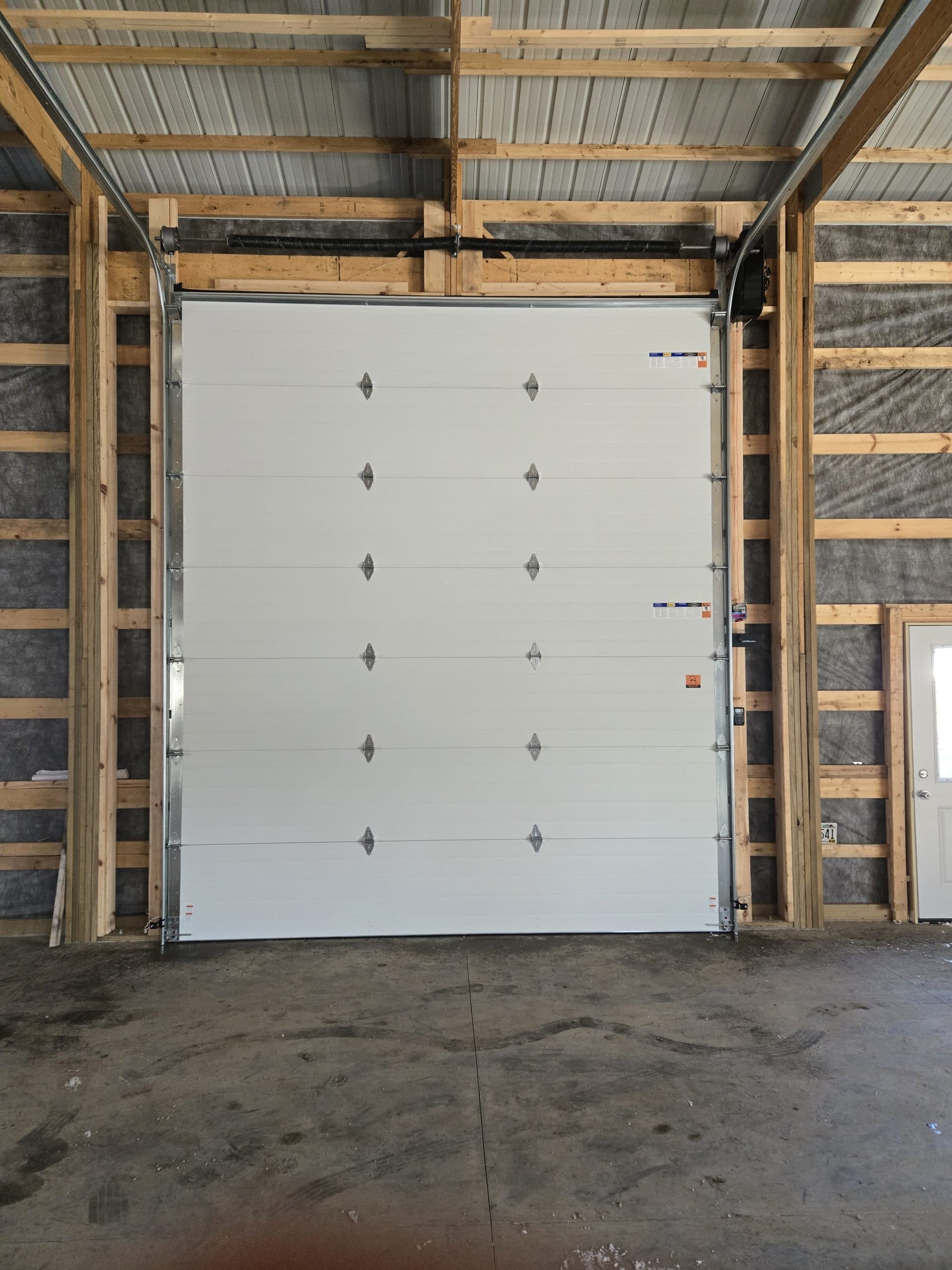 New garage door and opener installed inside a pole barn